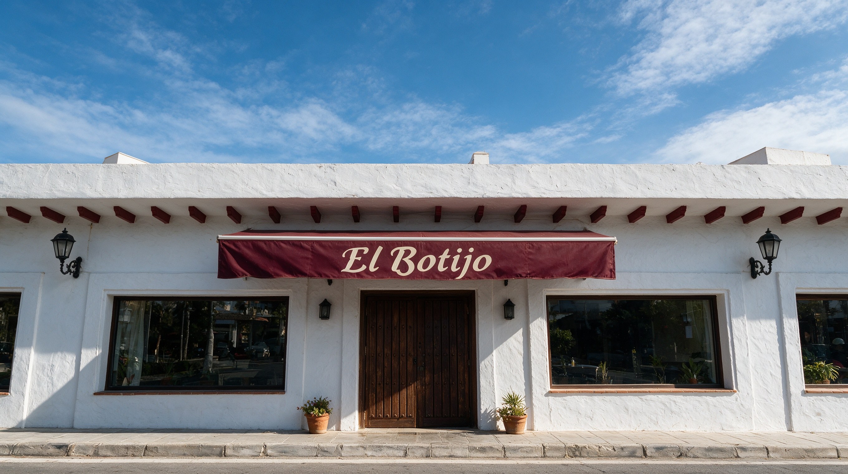 Fachada blanca con toldo granate que dice El Botijo sobre la puerta de un asador tradicional